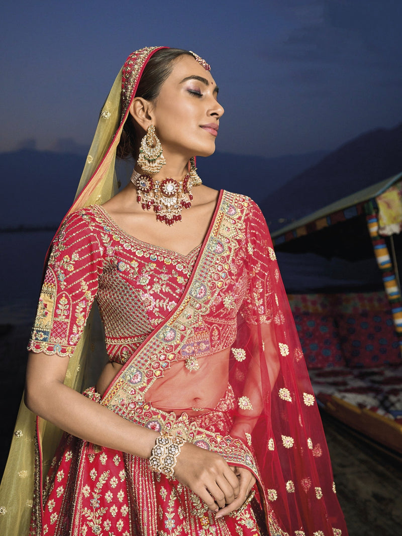 Woman in red silk lehenga with embroidered net dupatta by a lake.