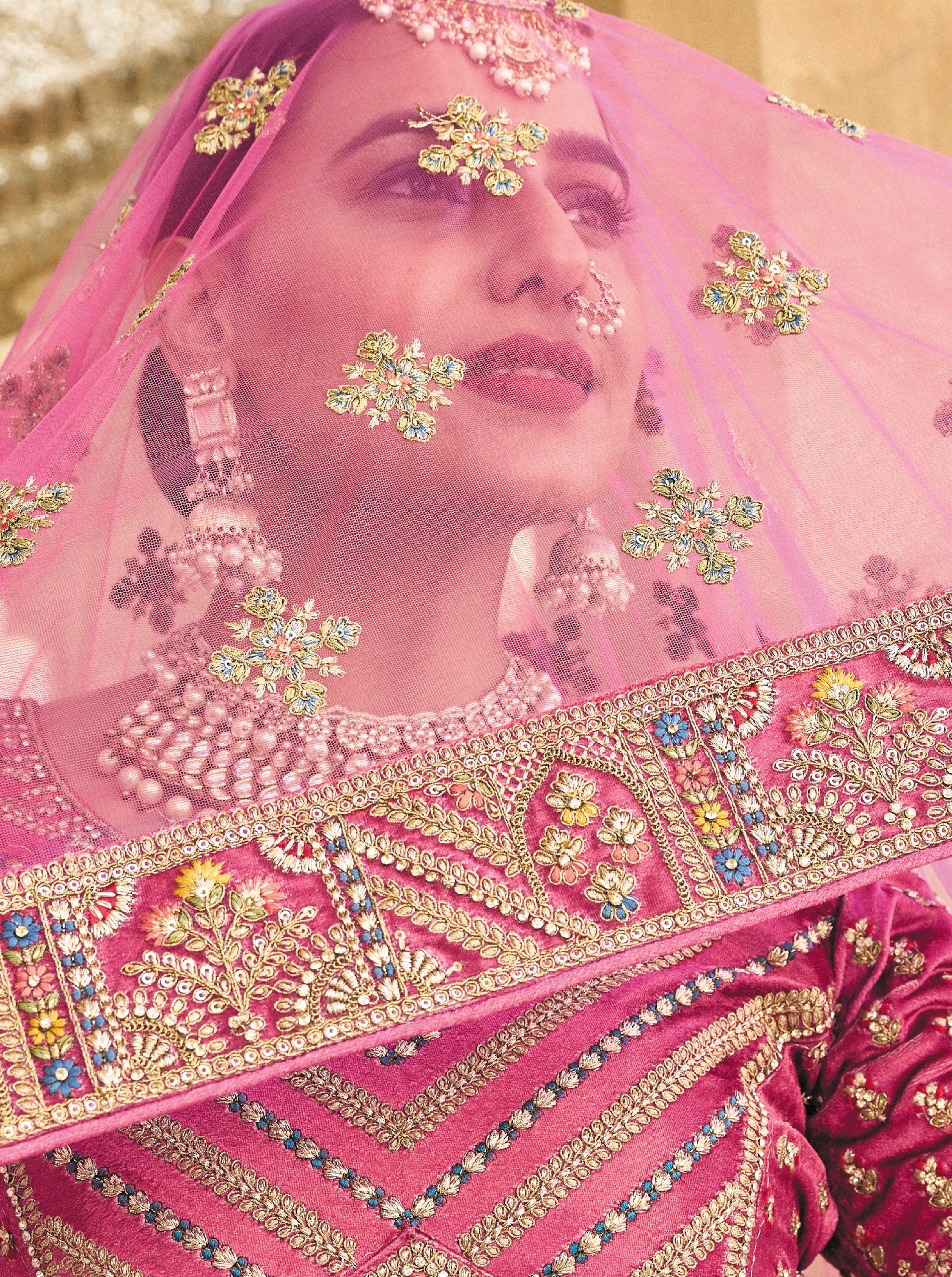 Elegant pink velvet lehenga with intricate embroidery and net dupatta.