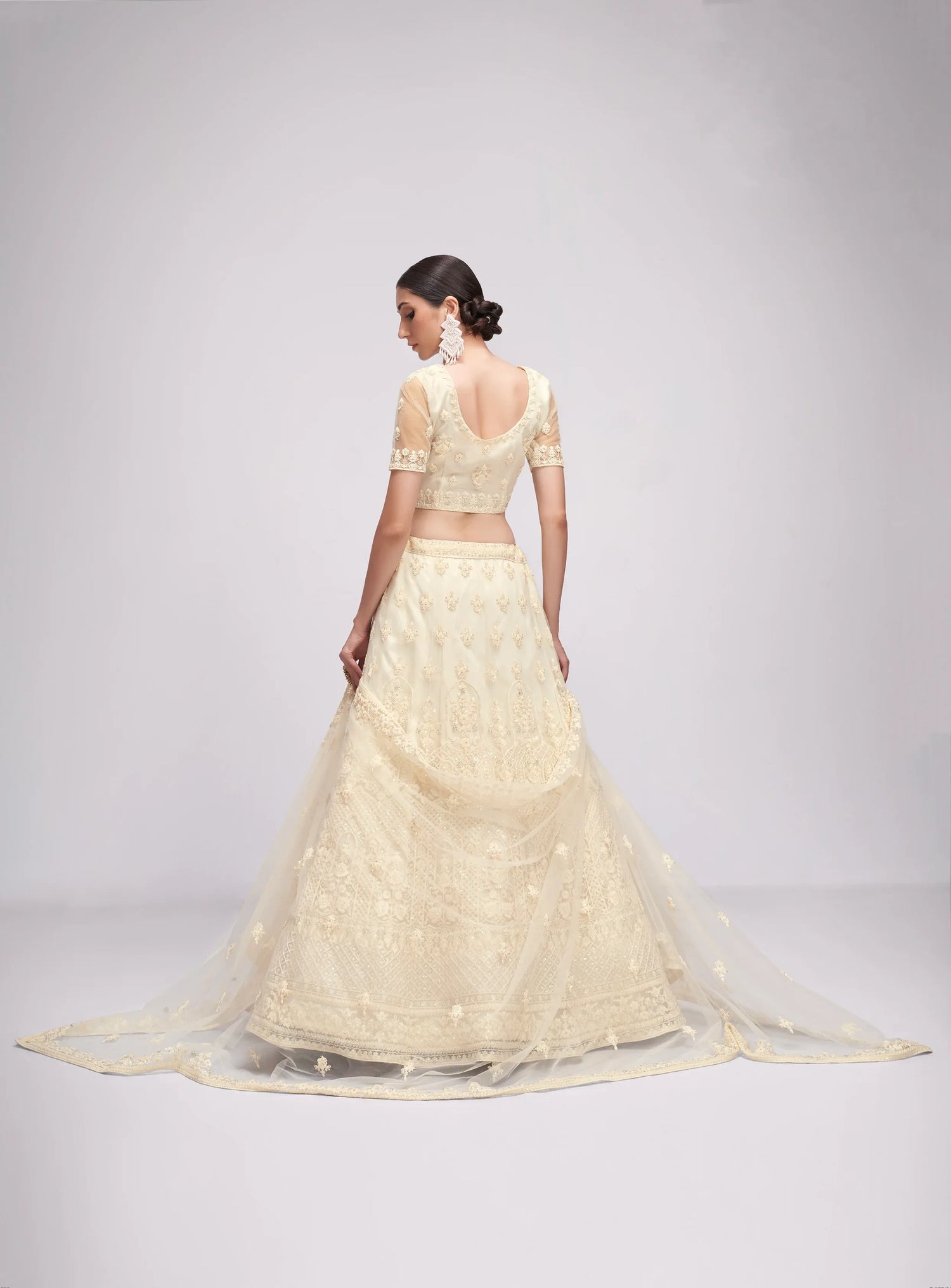 Elegant off-white net lehenga with intricate embroidery and stone embellishments.
