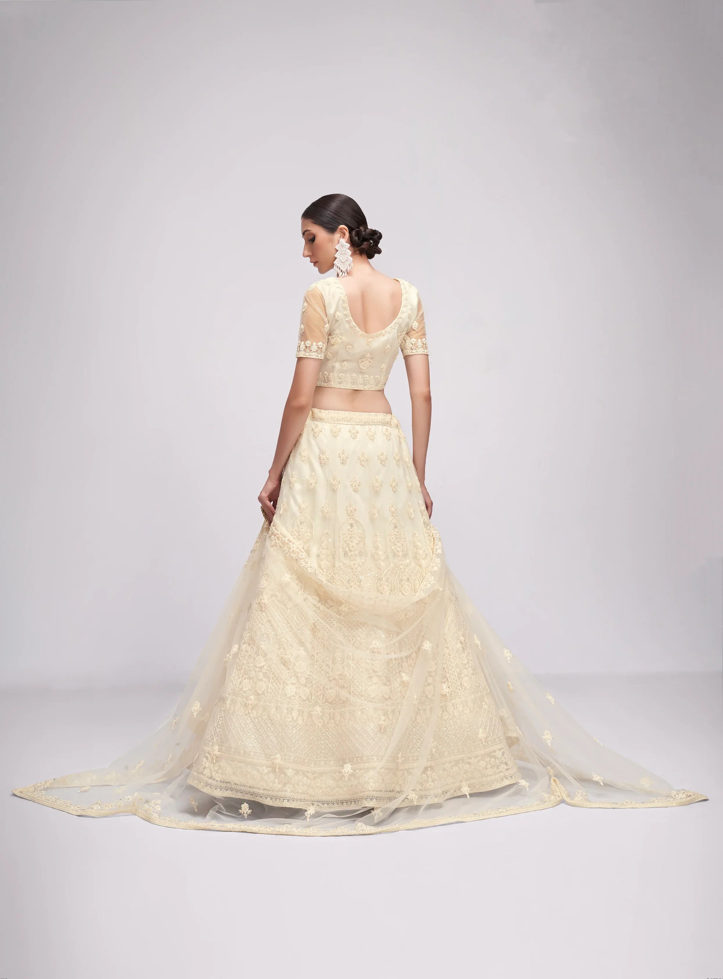 Elegant off-white net lehenga with intricate embroidery and stone embellishments.