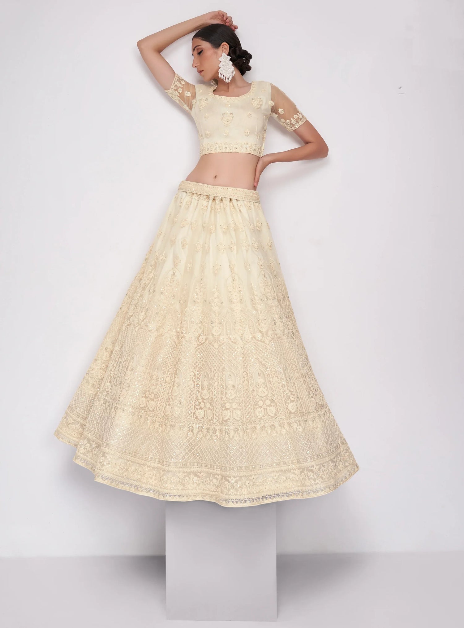 Elegant off-white net lehenga with intricate embroidery and stone embellishments.