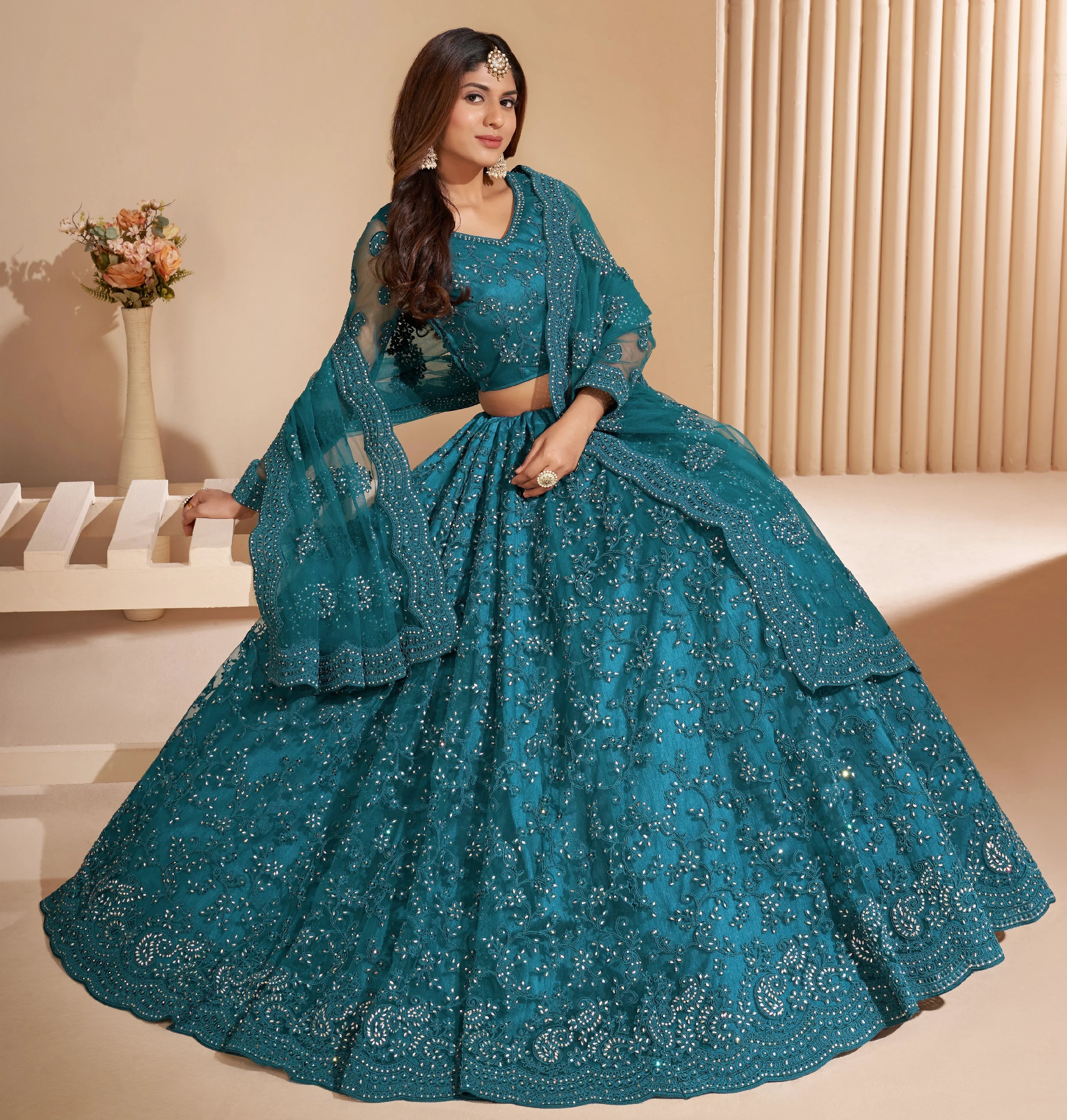Elegant teal net lehenga with silk inner and thread &amp; cording embroidery.