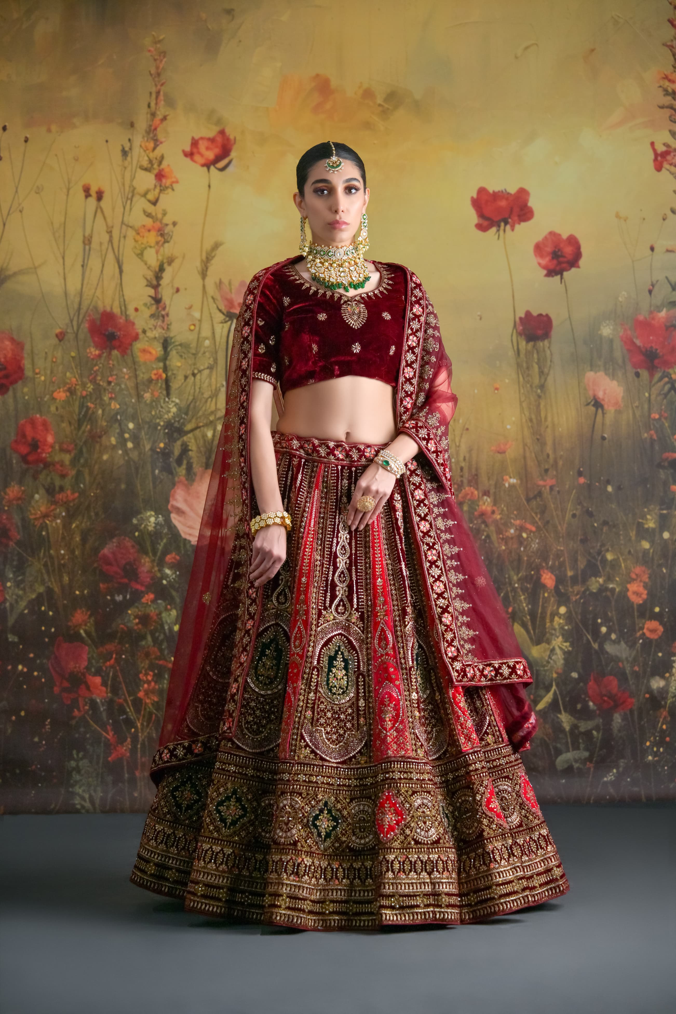 Velvet bridal lehenga choli in deep maroon and gold tones with traditional hand embroidery