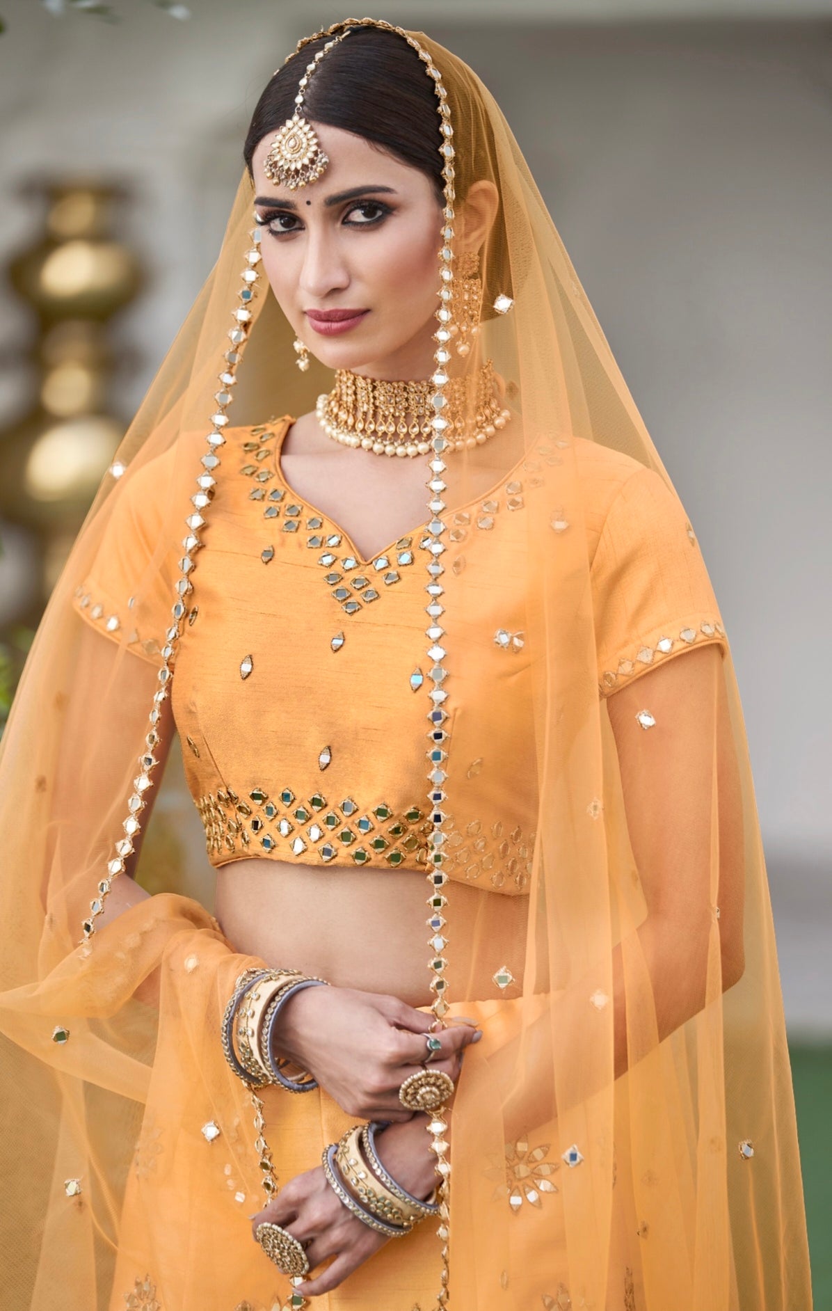 Close-up of yellow choli with intricate mirror detailing

